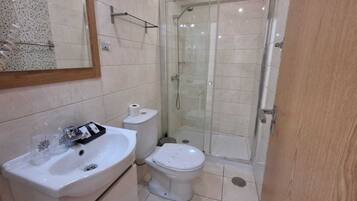 A bathroom with a sink, toilet, and glass-enclosed shower.