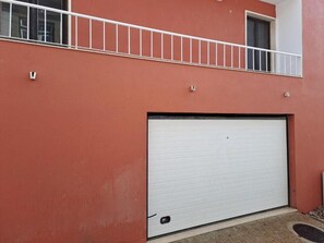 A building with a red exterior, a white garage door, and a balcony with a white railing. - Hotel Square (Serta)