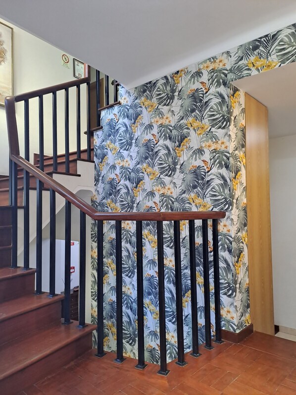 A staircase with a wooden handrail and black balusters, leading to an upper floor. - Hotel Square (Serta)