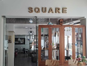 Fachada con un letrero que dice 'SQUARE' y un mueble de madera con puertas de vidrio que exhibe varios artículos.