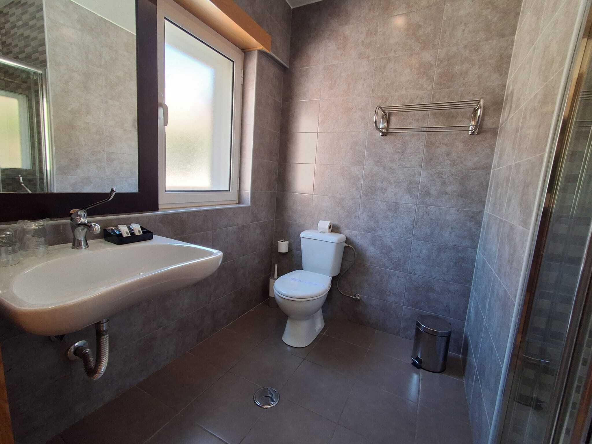 Un baño con lavamanos, inodoro y zona de ducha.