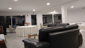 Un moderno vestíbulo de hotel con asientos de cuero, una mesa redonda con mantel blanco y un separador de vidrio.