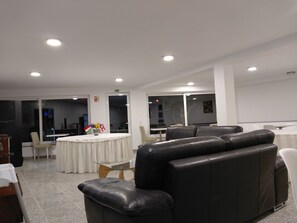 A modern hotel lobby with leather seating, a round table with a white tablecloth, and a glass partition. - Hotel Square (Serta)