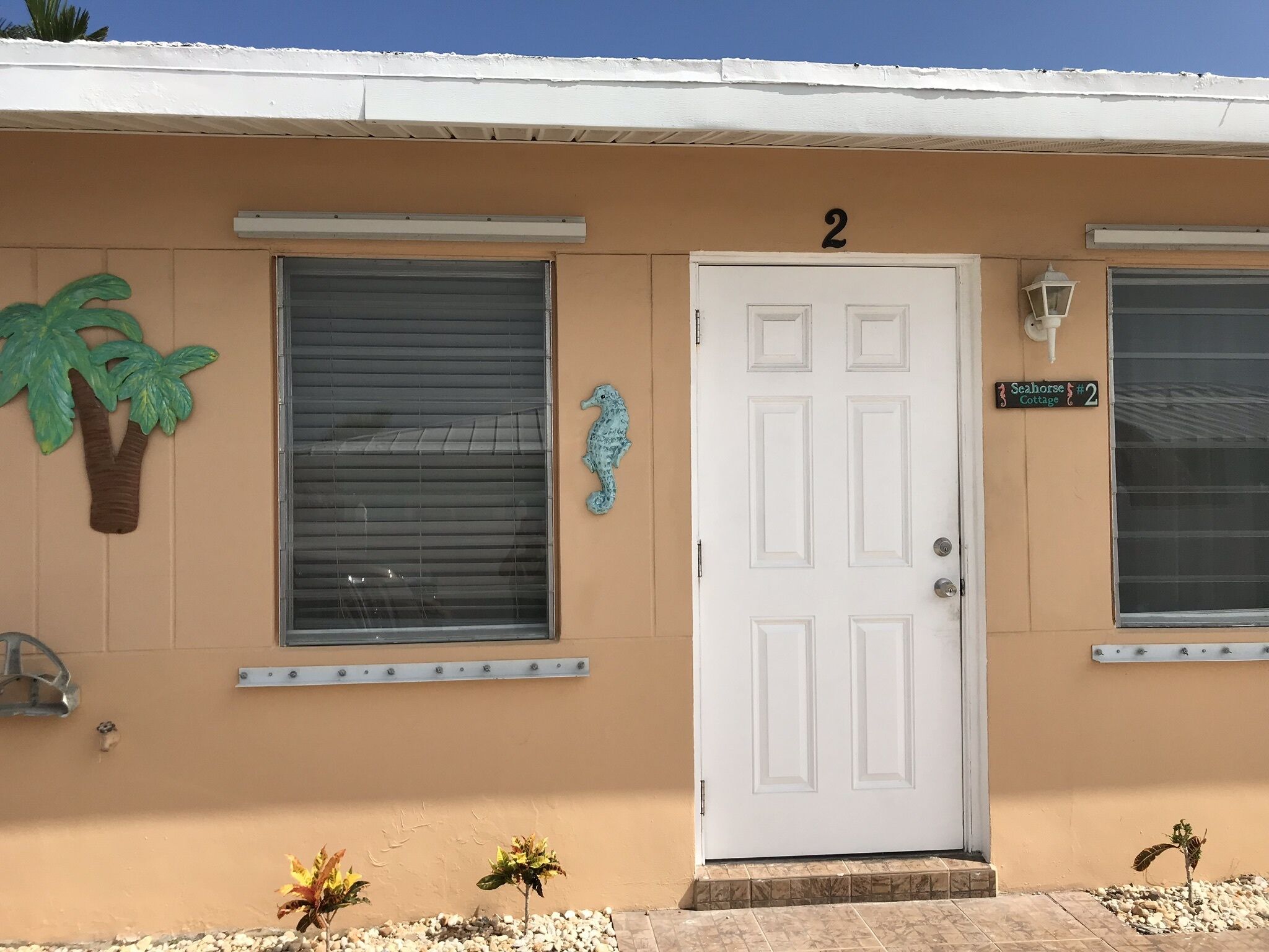 A building with a white door, two windows, and a small sign above the door.