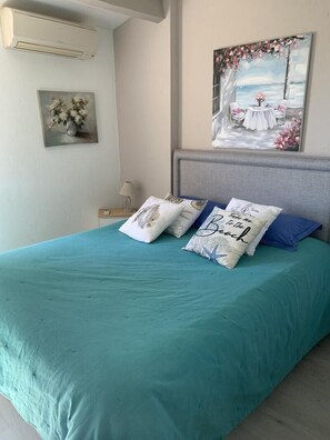 Un lit avec une couvre-lit turquoise, une tête de lit et des coussins décoratifs.