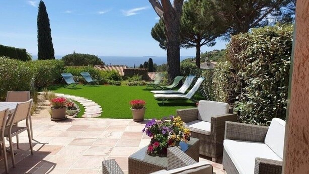 Un patio con mobiliario exterior, césped y vista al mar.