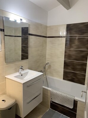 A bathroom with a sink, mirror, vanity, toilet, shower, and towel rack. - Joli Gîte les Palmiers III (LA CROIX VALMER)
