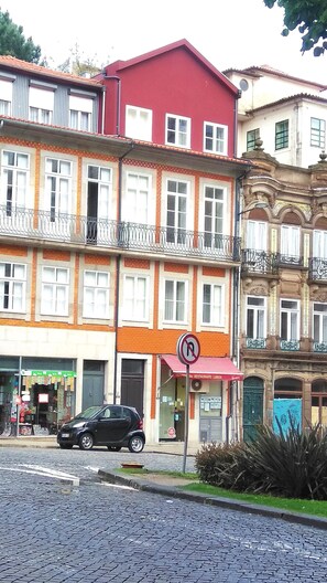 A multi-story building with a red roof, a ground-floor restaurant, and a black car parked in front.