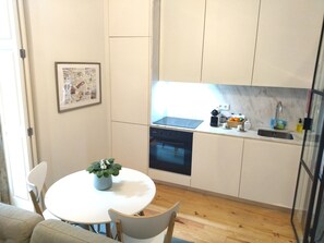 Cozinha compacta com mesa, cadeiras, um pequeno vaso de planta, lava-louças e pia.