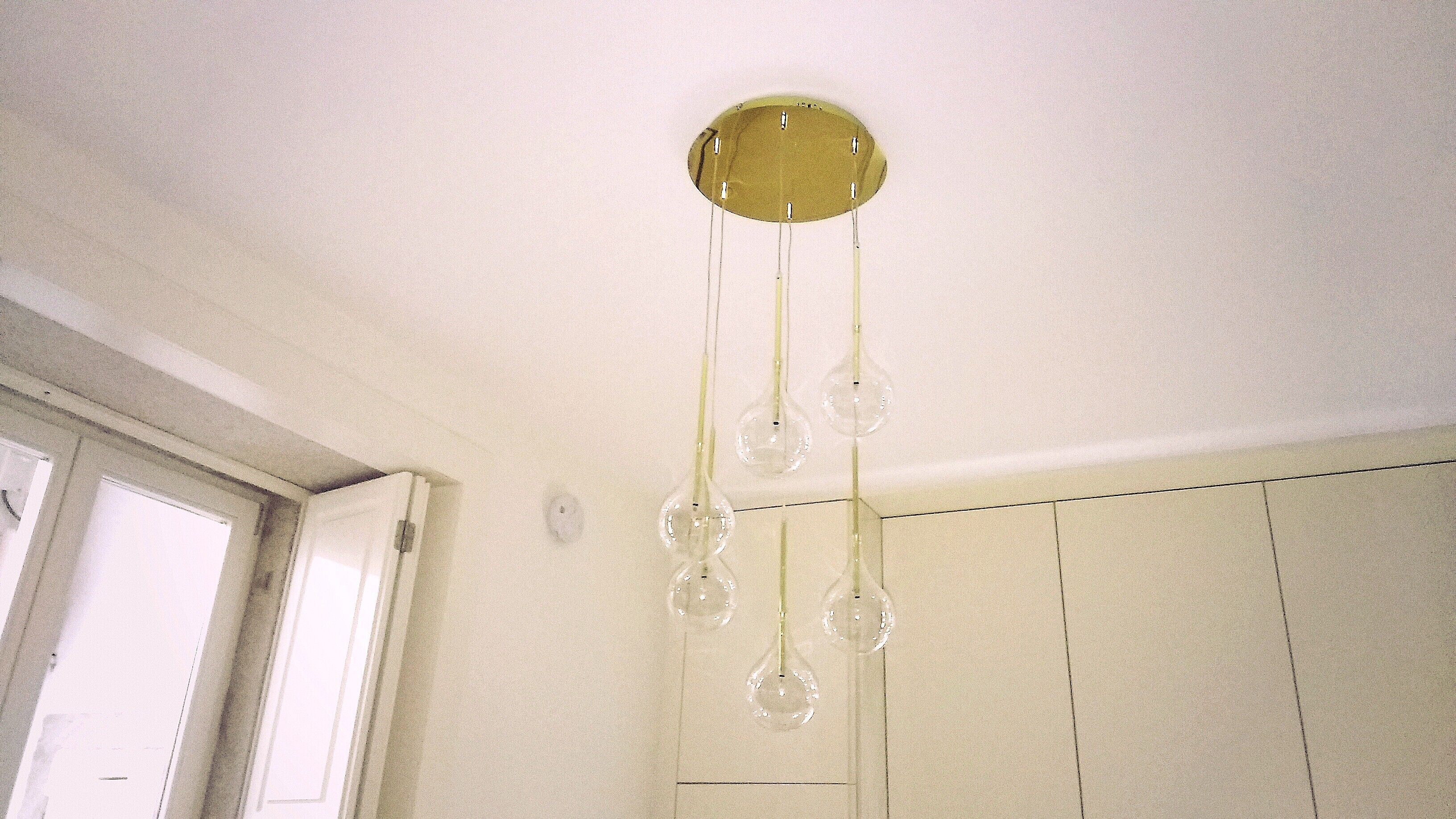 A room with a ceiling light fixture with multiple bulbs and a door with a white frame.