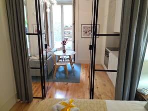 Um quarto com cama, uma mesa de jantar com cadeiras, um sofá e uma cozinha.