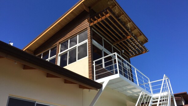 Un immeuble à plusieurs étages doté d’une façade en bois, de grandes fenêtres et d’un escalier blanc menant à un niveau supérieur.