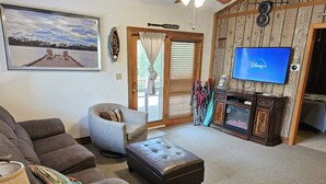 Ein Wohnzimmer mit einem großen Flachbildfernseher, einem Sofa, einem Sessel und einer Holzkommode.
