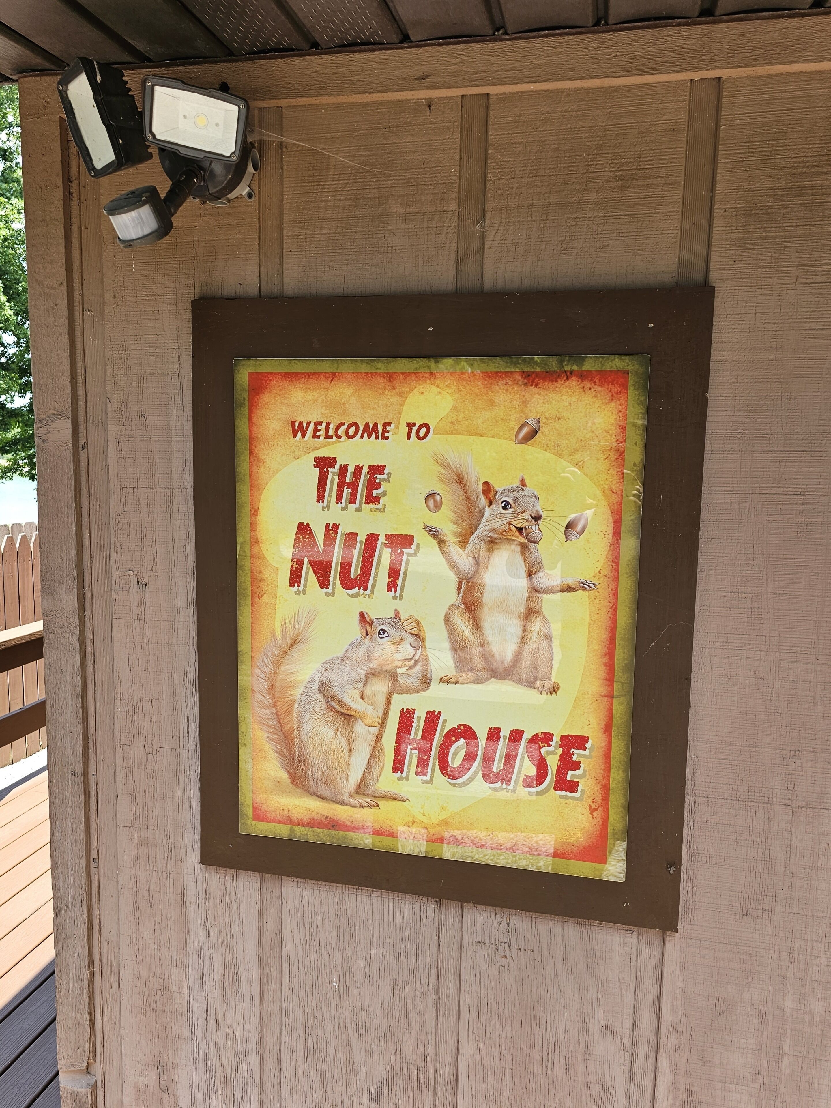 A framed welcome sign for 'The Nut House' with two squirrels and a yellow background.