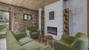 Ein gemütliches Zimmer mit einer Steinwand, einem Kamin und grünen Polsterstühlen.