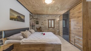 Ein Schlafzimmer mit einem hölzernen Bett, Steinwänden und einem großen Fenster.