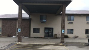 A building with a covered entrance, brick pillars, and a parking lot with marked spaces. - AmericInn by Wyndham Viroqua (Viroqua)