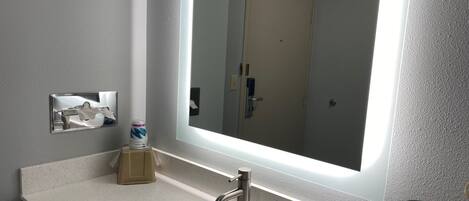 A bathroom with a large mirror, a sink, and a toilet.