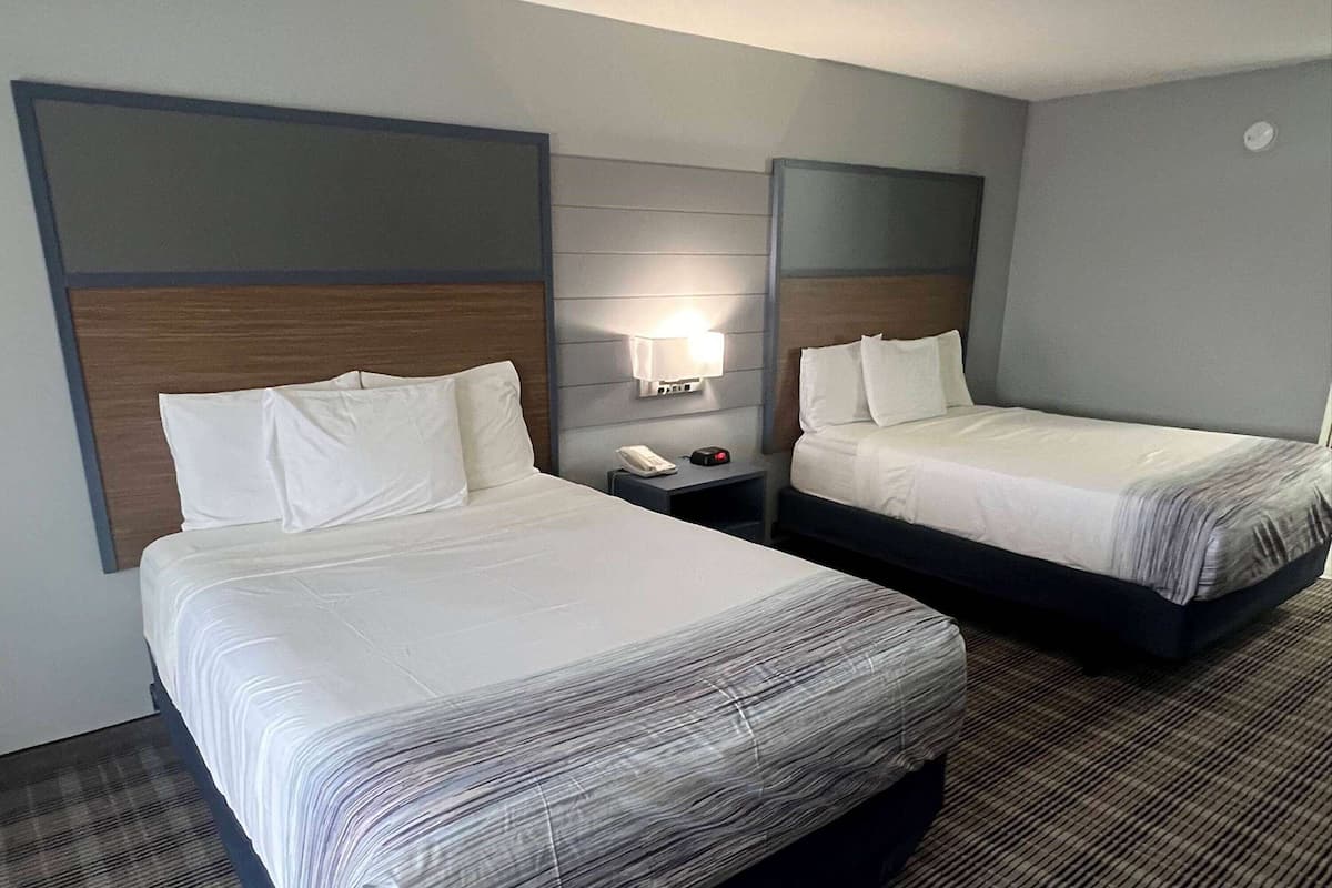 Ett hotellrum med två sängar, ett nattduksbord med en telefon och en lampa samt ett rum med heltäckningsmatta.