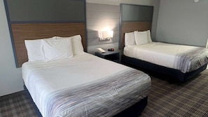 A hotel room with two beds, a nightstand with a phone and a lamp, and a carpeted floor. - AmericInn by Wyndham Viroqua (Viroqua)