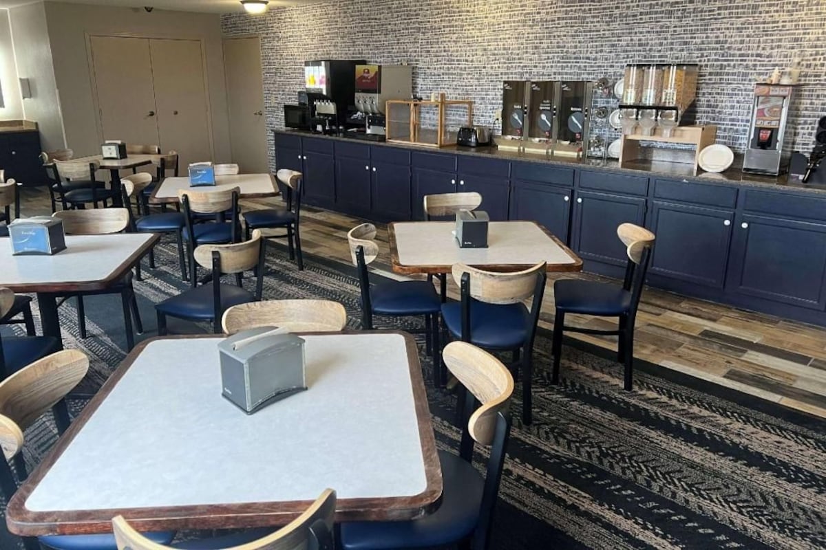 Un restaurant avec des tables et des chaises, un comptoir avec une machine à café et un mur en briques.