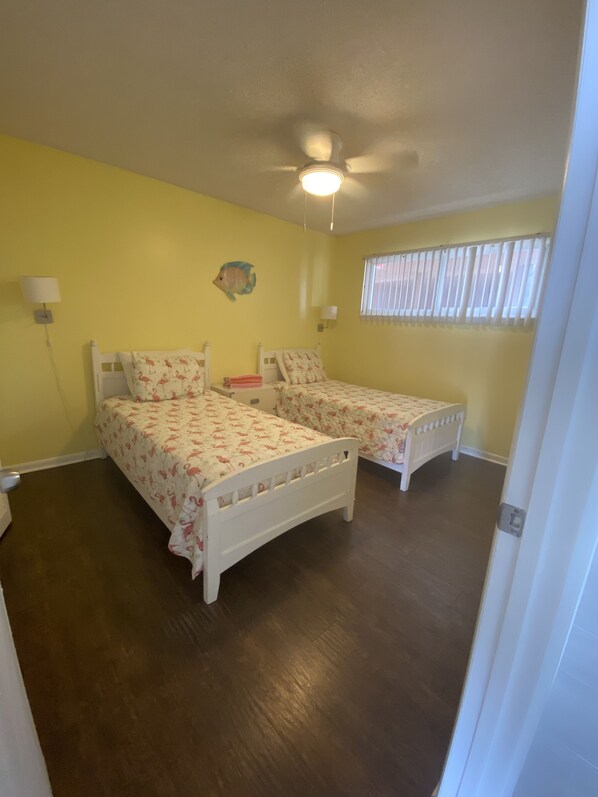 A room with two single beds, a ceiling fan, a fish wall decoration, and a window with blinds. - Oceanfront FANTASTIC VIEW, large balcony, 2/2 condo (Cocoa Beach)