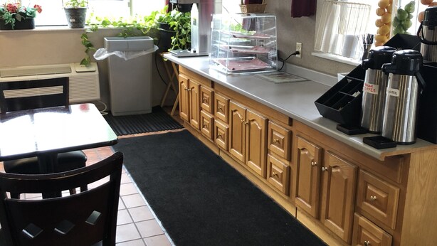 A kitchen with a dining area, a TV mounted above the counter, and a window with curtains. - Latham Inn (Latham)
