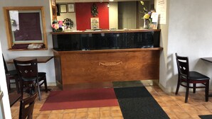 A reception area with a wooden counter, a red wall, and a tiled floor. - Latham Inn (Latham)