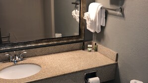 A bathroom with a sink, mirror, towel rack, toilet, and toilet paper. - Latham Inn (Latham)