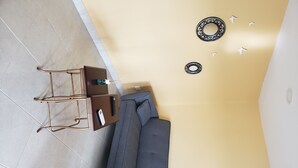 A room with a sofa, a small table with a remote control, and decorative wall art.