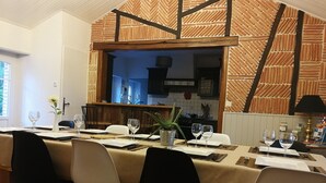 A dining area with a long table set for a meal, chairs, and a view into the kitchen. - A peaceful holiday 8 minutes from the beach (le perrier)