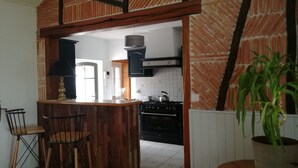 A kitchen with a herringbone-patterned brick wall, a wooden island with a sink, and a potted plant. - A peaceful holiday 8 minutes from the beach (le perrier)