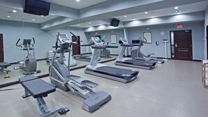 A gym with treadmills, elliptical machines, and a bench.