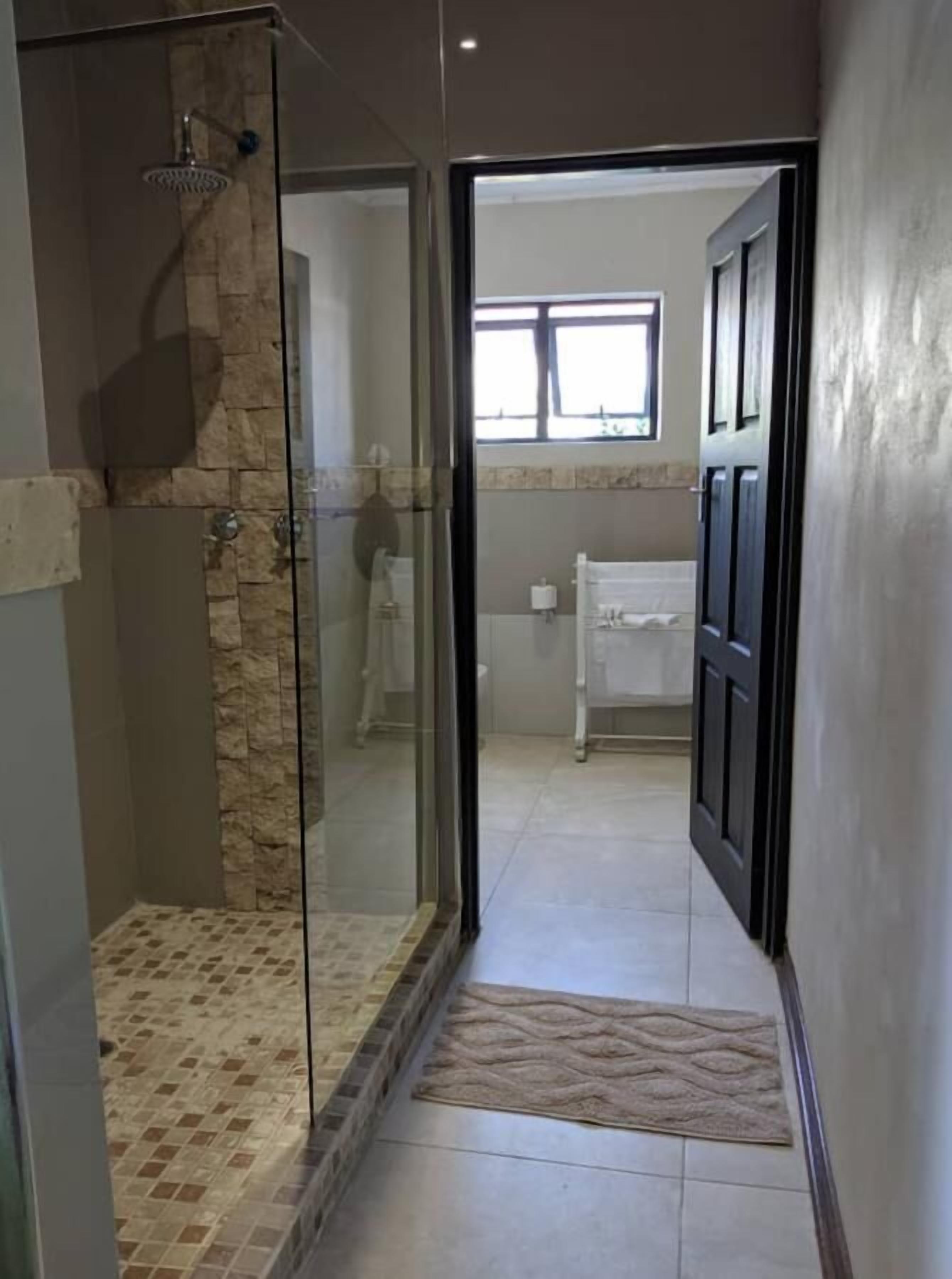 Une salle de bain moderne avec une douche à parois de verre, des toilettes apparentes et un porte-serviettes.