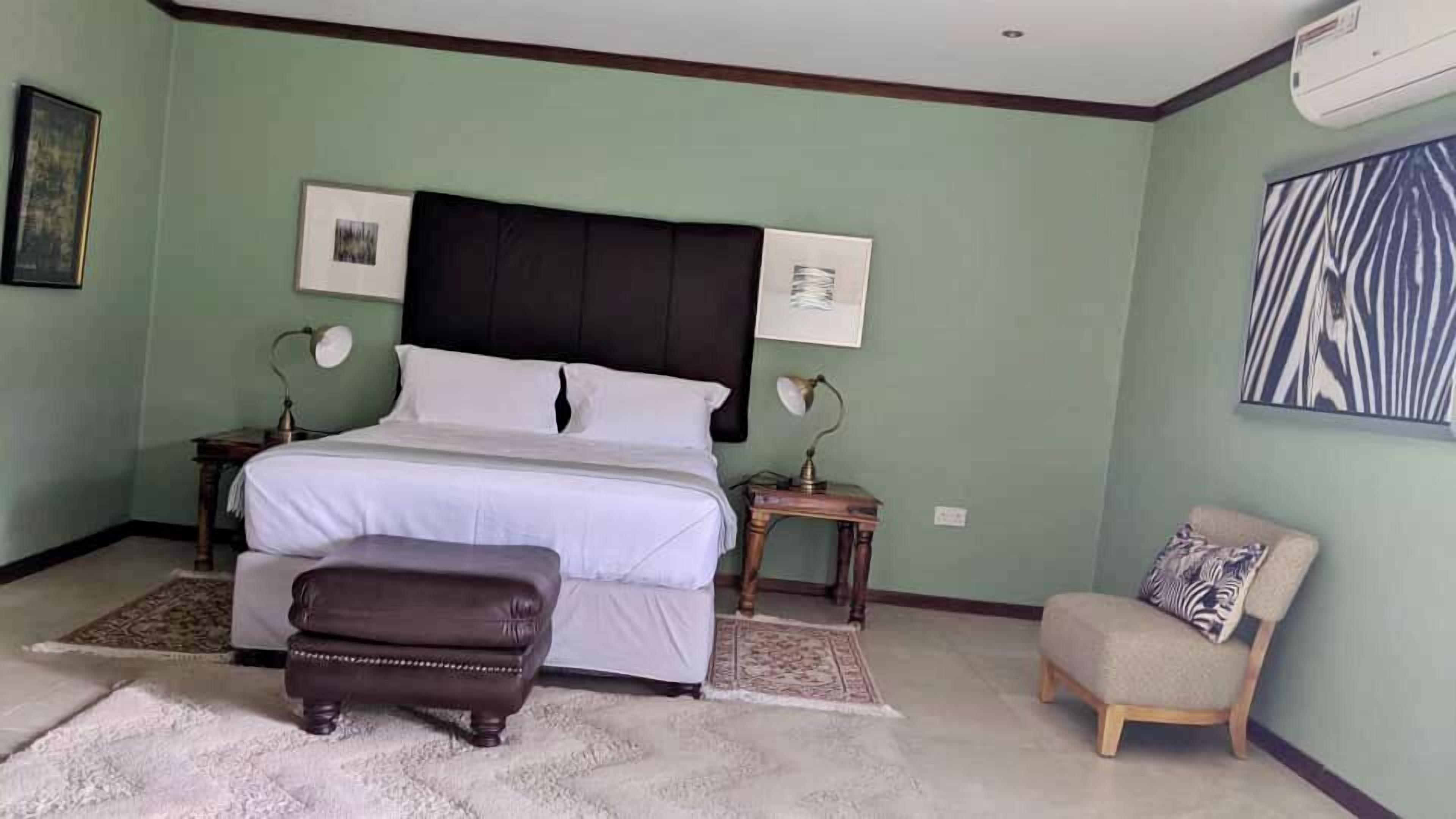 Un dormitorio con cama, mesitas de noche, una silla y una alfombra.