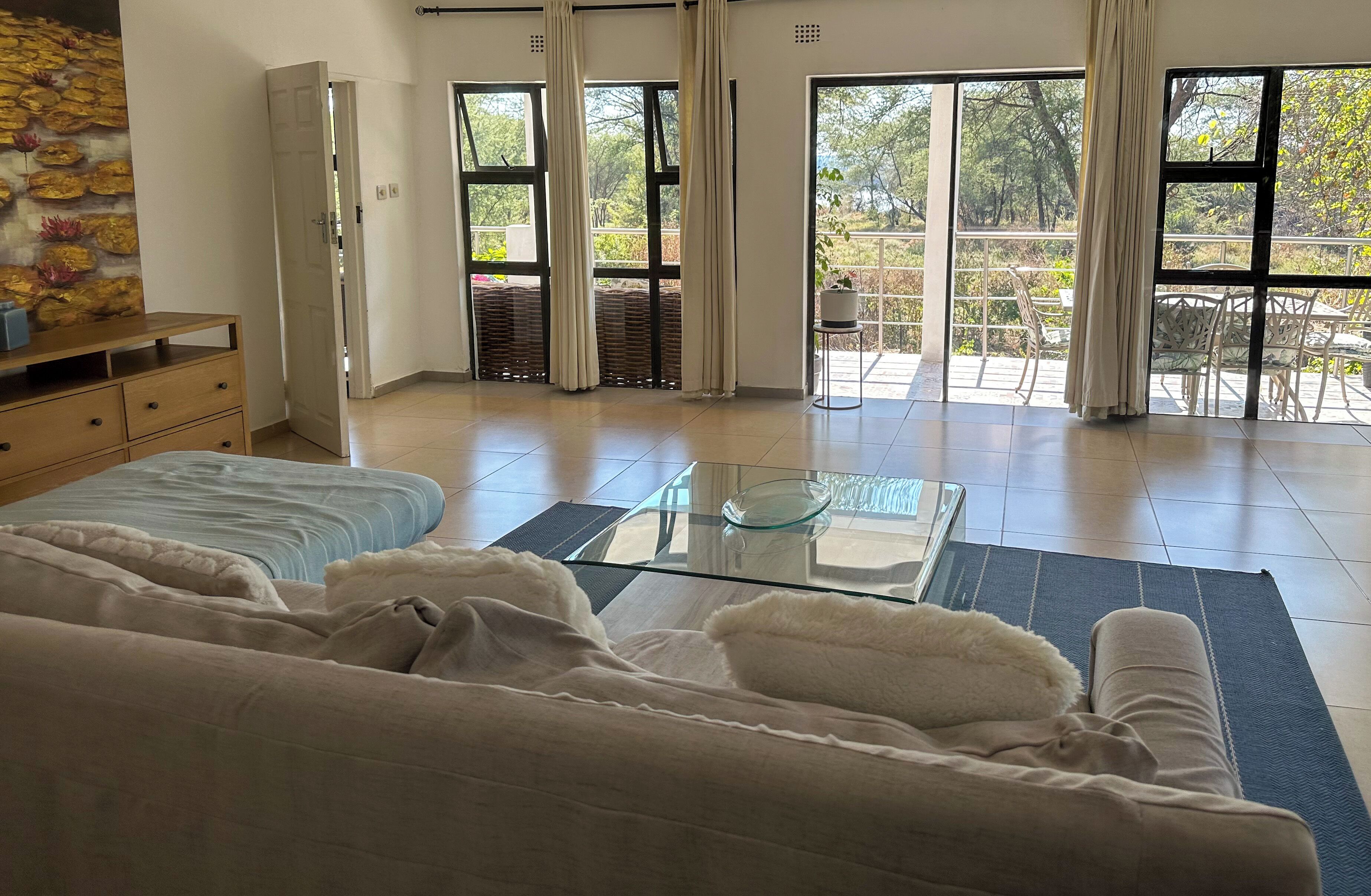 Habitación amplia con cama, una mesita de centro de vidrio y vistas al exterior a través de grandes ventanales.