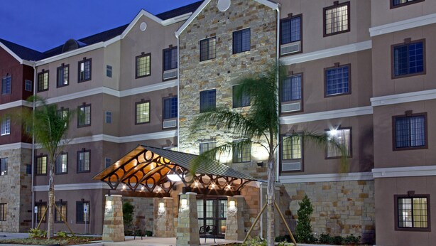 A multi-story hotel with a stone facade, multiple windows, and a covered entrance area. - Free Breakfast + Outdoor Pool + 24 Hour Fitness Center (Stafford)
