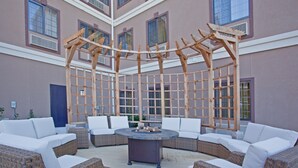 A covered outdoor seating area with wicker furniture and a central fire feature. - Free Breakfast + Outdoor Pool + 24 Hour Fitness Center (Stafford)