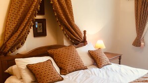 A neatly made bed with patterned pillows and a canopy, a bedside table with a lamp, and a framed picture on the wall. - Groom's Cottage  a fabulously quiet paradise in the heart of the Peak District (Castleton)