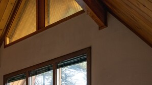 A room with large windows, a bed, a nightstand with a lamp, and a wooden ceiling. - Leavenworth Cabin Close To Town And Jaw Dropping View! (Leavenworth)