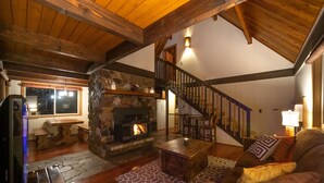 A cozy living room with a stone fireplace, wooden ceiling beams, a staircase, and a comfortable seating area. - Leavenworth Cabin Close To Town And Jaw Dropping View! (Leavenworth)