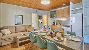 Eine moderne Küche mit Holzausstattung, einem Esstisch für vier Personen und einer Wohnbereich mit Sofa und Couchtisch.