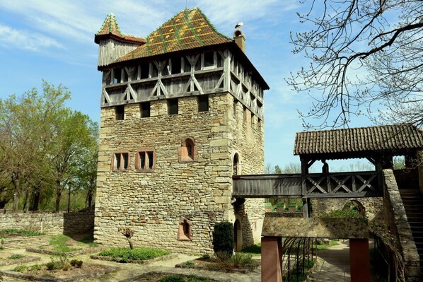 A stone tower with a wooden upper section, a small bridge, and a pathway leading to it.