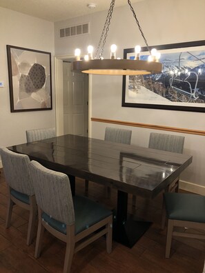 Enjoy meals in a stylish dining area with a large table and six chairs, surrounded by artwork and a pendant light.