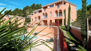 A multi-story building with balconies, a swimming pool, and a well-maintained garden.