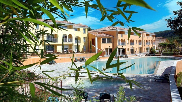 A resort with a swimming pool, multiple-story buildings, and outdoor seating areas.