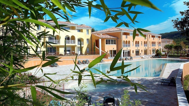 Un resort con piscina, edificios de varios pisos y zonas de estar al aire libre.