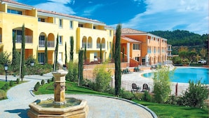 A hotel with a swimming pool, outdoor seating, and a fountain.