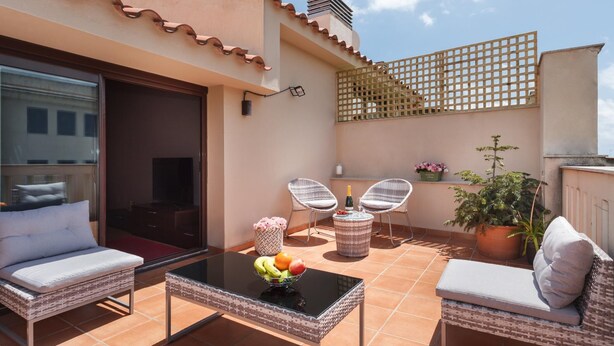 Una terraza en la azotea con mobiliario exterior, una mesa con fruta y plantas en macetas.