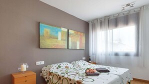 Un dormitorio con dos camas, un aparador de madera, un ventanal con cortinas y arte abstracto en la pared.